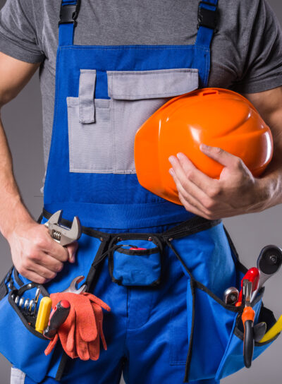 Builder with tools in hand to build on gray background. Turnkey Projects